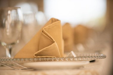 Sıralar dolusu bej keten katlanmış peçeteler akşam yemeğinde cam tabaklarda.