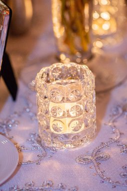 Altın dekoratif cam mum tutacağı düğün resepsiyonunda masanın üstünde.