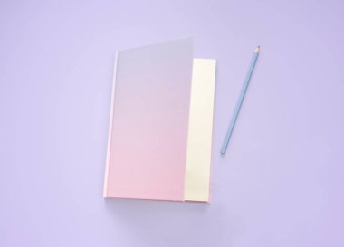 düz defter ve kırtasiye malzemesi mor pastel zeminde.