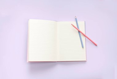 düz defter ve kırtasiye malzemesi mor pastel zeminde.