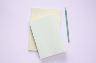 düz yeşil renkli kitap ve kırtasiye mor pastel zeminde