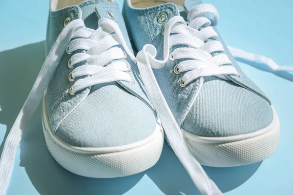 Sepatu biru dengan tali putih dengan latar belakang biru muda. — Stok Foto