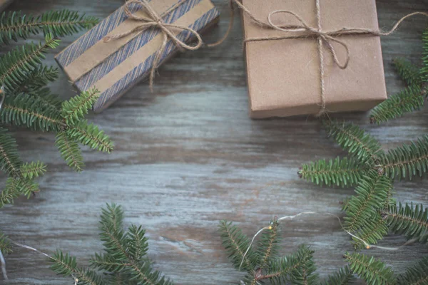 Coffrets cadeaux enveloppés dans du papier artisanal, des branches de sapin et des guirlandes. — Photo