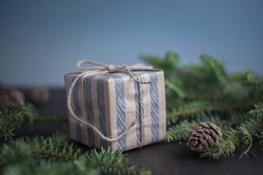 Noel arkaplanı. El işi kağıdına sarılı hediye kutusu, köknar dalları. Yeni yıl havası.