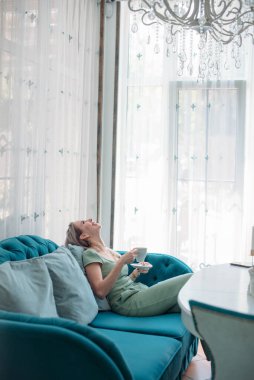 Kafedeki masada oturan çekici bir kadın kahve içiyor..