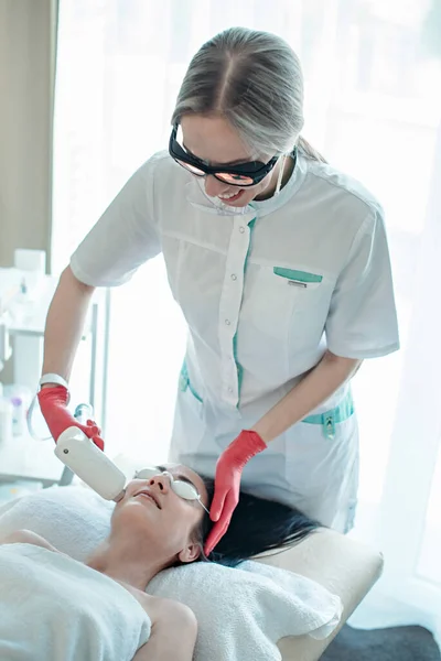 A beautician makes a diode laser rejuvenation procedure. — Stock Photo, Image