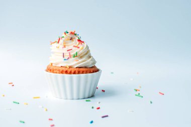 Homemade cupcake with colorful sprinkles on a white background.