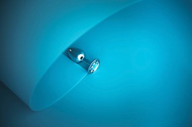 Metal butt plug on a blue creative background.