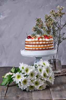 Taze böğürtlenli, çiçekli ve şekerli bal pastası. Pastanın katları krem peynir kremine batırılmış. Tahta tezgahta tatil pastası.