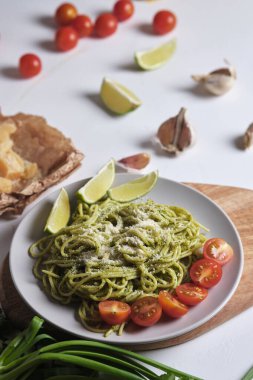 Pesto, domates ve limonlu makarna. Parmesan peynirli spagetti ve mutfak masasında yemek malzemeleri. Ev yapımı İtalyan yemekleri..