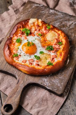 Jambonlu, peynirli, yumurtalı, domates soslu ve şifalı hamur hamurlu Rustik pizza. Tahta bir masada iştah açıcı ve lezzetli yemekler..