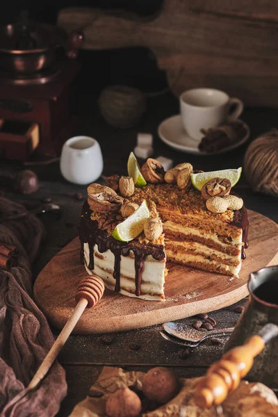 Classic homemade honey cake. A birthday cake with honey, chocolate, nuts and nut butter. Dessert on a wooden board.