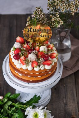 Taze böğürtlenli, çiçekli ve şekerli bal pastası. Pastanın katları krem peynir kremine batırılmış. Tahta tezgahta tatil pastası.