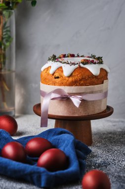 Paskalyayı kutlamak için ev yapımı kek ve kırmızı yumurta. Paskalya sembolleri. Kurumuş çiçeklerle süslenmiş Paskalya pastası, taze otlar, krema ve kurdele..