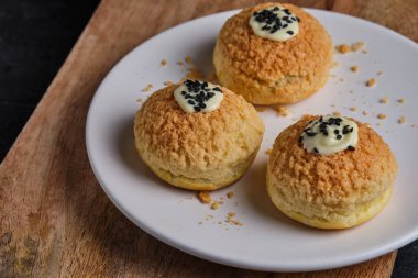 Krem peynirli Fransız choux kekleri, çikolatalı krema ve siyah susam tohumlarıyla süslenmiş..