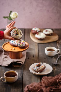 Kahvaltıda üzerine beyaz çikolata parçacıkları serpilmiş çörekler. Çiçekli ve şekerli çocuklar için sabah çayı.