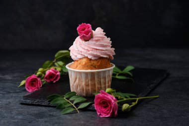 Güllerle süslenmiş kek. Siyah bir tabakta tatlı. Koyu arkaplanda kekler.