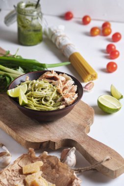 Pesto soslu makarna, tavuk ve limon. Parmesan peynirli spagetti ve mutfak masasında yemek malzemeleri. Ev yapımı İtalyan yemeği..