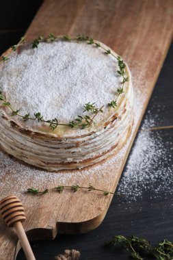 Kremalı kremalı krep, krema şekeri ve kekik filizi ile süslenmiş. Büyük bir tahtanın üzerinde tatlı. Eski bir kırsal mutfak masasında tabak.