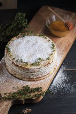 Kremalı kremalı krep, krema şekeri ve kekik filizi ile süslenmiş. Büyük bir tahtanın üzerinde tatlı. Eski bir kırsal mutfak masasında tabak.