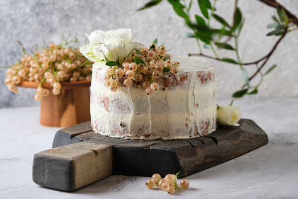 Homemade sponge cake with cream cheese cream and white currant filling. Festive dessert decorated with flowers.