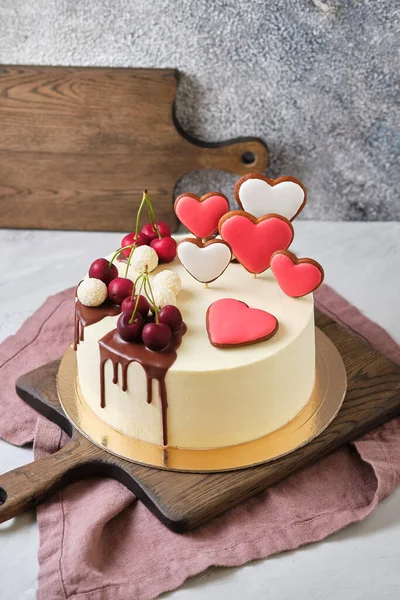 Delicious and beautiful handmade cake. Confectionery for the holiday. The dessert is decorated with fresh berries, sweets and gingerbread in the shape of a heart.