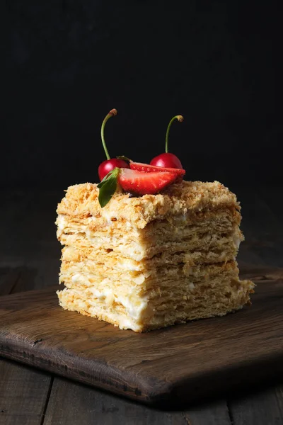 Layer cake in a cut. Custard cake, decorated with crumbs and fresh berries.