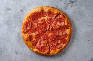 A closeup of a pepperoni pizza. Pizza with spicy sausage, tomato sauce and mozzarella cheese. Flat lay. On a light background