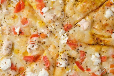 Pizza with tomatoes, chicken, onions, feta cheese, mozzarella cheese and spices. A closeup of a pizza.
