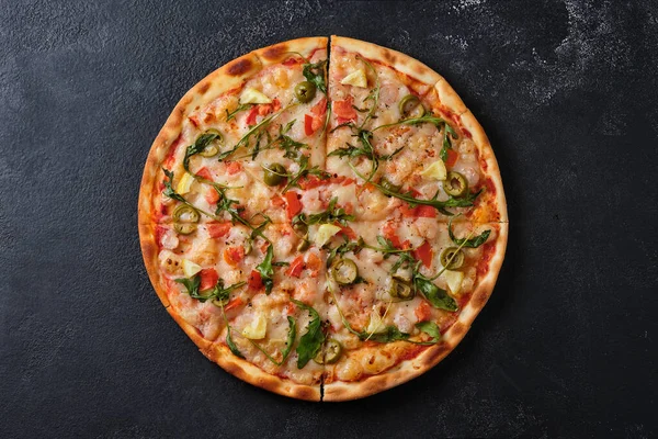Pizza with tomatoes, shrimps, arugula, olives, lemon, mozzarella cheese, spices and tomato sauce. Flat lay. On a dark background.