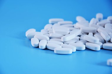 Mavi arka planda beyaz haplar. Tıbbi haplar, makro görüş.