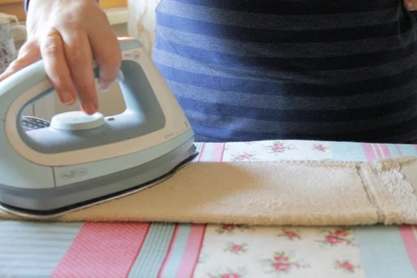 Strijkservice een handdoek met een stoomstrijkijzer op een strijkplank — Stockfoto