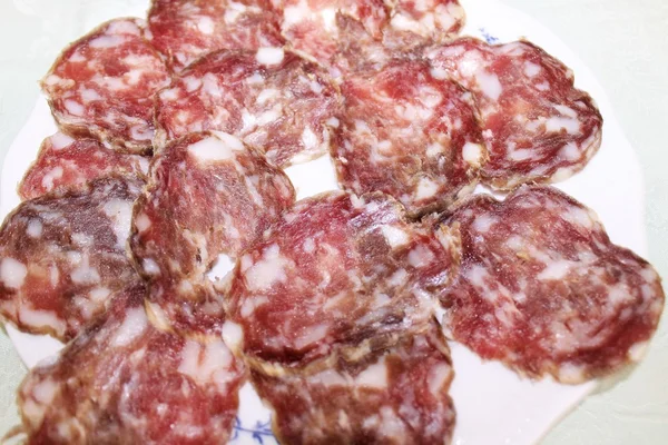 Skivor av italienska salami på vit platta — Stockfoto