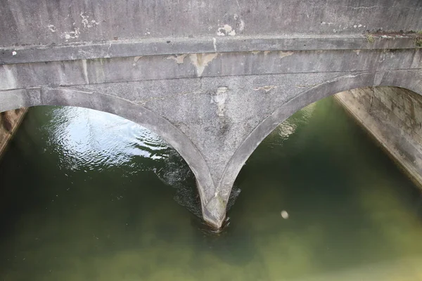 非常に古い石造りの橋のアーチの近くと川の水が下に流れる橋の下 — ストック写真