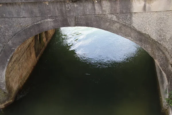 非常に古い石造りの橋のアーチの近くと川の水が下に流れる橋の下 — ストック写真