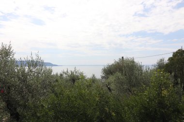 İtalya 'daki Garda Gölü. Mavi su, beyaz bulutlar, sisli dağlar. Tatil kavramı