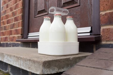 Fresh semi skimmed milk in recyclable glass bottles delivered to the door by a traditional milk man in the UK clipart