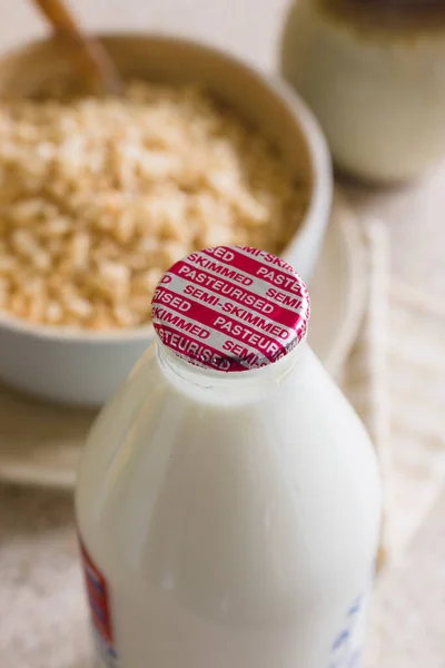 新鮮な半脱脂ミルクでリサイクル可能なガラスボトルをドアのステップに伝統的な牛乳男によって配信 — ストック写真