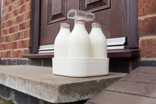 英国の伝統的なミルクマンによってドアに配信リサイクル可能なガラスボトルで新鮮な半脱脂ミルク — ストック写真