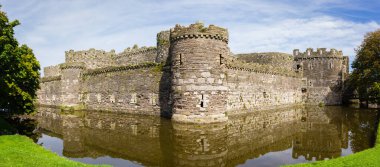 The ruins of Beaumaris Castle built in the 14th century by Edward the first as part of his military fortifications to conquer Wales. It is now a scheduled ancient monument clipart