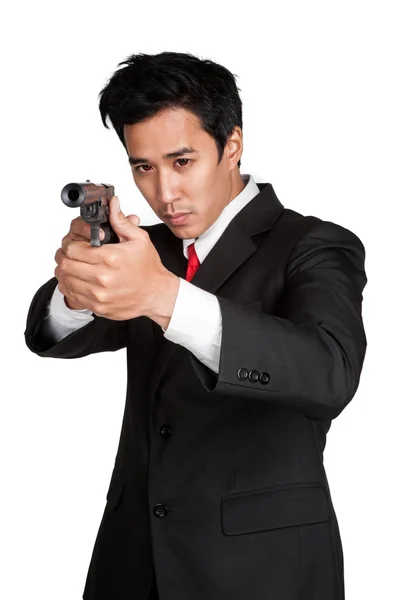 Uomo d'affari asiatico tenere pistola in tuta isolato Immagine Stock