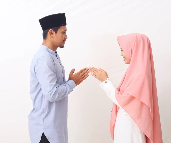 Portrait of asian man and woman greeting in muslim traditional way touching tip of finger. Asian Muslims are celebrating Eid Mubarak. Isolated on white background.