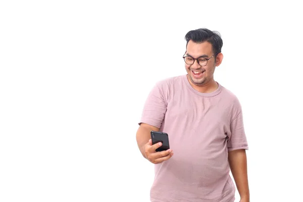 Gözlüklü ve mor gömlekli mutlu Asyalı erkek portresi akıllı telefon tutarken ayakta duruyor. Bazı iyi haberleri var. Beyazda izole edilmiş