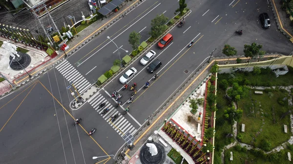 Aerial view of cars and motorbikes at traffic lights during the day.
