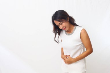Güzel Asyalı kız karnını tutarken ayakta duruyor. Sağlık hizmeti konsepti. Kopyalama alanı ile beyaz arkaplanda izole