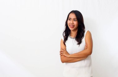 Güzel genç Asyalı kız kollarını kavuşturup boş alana bakarken gülümsedi. Beyaz arkaplanda izole