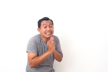 Asyalı bir adamın komik yüzü, yaptığı hata için af diliyor. Beyaz arkaplanda izole