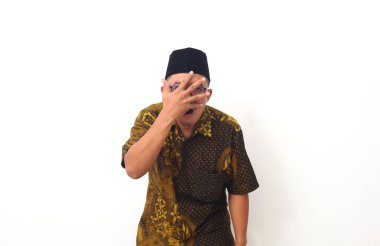 Korkak Asyalı adamın portresi, beyaz arka planda tek başına duran, elleriyle yüzünü kapatıyor. İnsan duyguları, yüz ifadesi konsepti. Ön görünüm