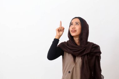 Duvak takan mutlu Asyalı Müslüman kadın portresi ya da tesettürlü ve boş bir yere bakarken bir şey gösteren tesettür. Kopya alanı ile beyaz arkaplanda izole