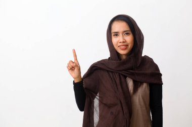 Duvak takan mutlu Asyalı Müslüman kadın portresi ya da tesettürlü ve kendinden emin bir şekilde bir numaralı parmaklarıyla işaret eden tesettür. Kopya alanı ile beyaz arkaplanda izole